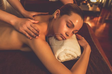 Téléchargez les photos : Couple caucasien client appréciant relaxant massage spa anti-stress et dorloter avec beauté loisirs de la peau dans la bougie chaude éclairage spa salon d'ambiance à la station de luxe ou hôtel. Tranquillité - en image libre de droit