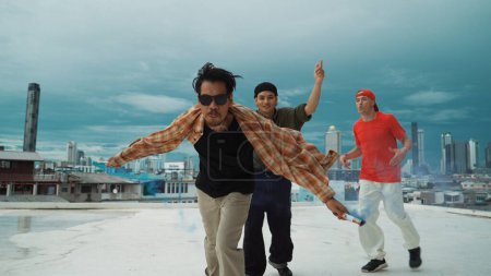 Photo for Group of multicultural hipster playing color flare at rooftop. Attractive street dancer holding colored smoke and perform break dance move to hip-hop music. Outdoor sport 2024. Endeavor. - Royalty Free Image