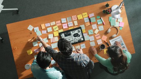Téléchargez les photos : Time lapse of creative designer working together brainstorming idea en utilisant des notes collantes à la table de réunion avec des palettes de couleurs. Vue aérienne de l'équipe intelligente choisissant l'icône graphique de la tablette. Symposium. - en image libre de droit