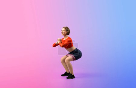 Photo for Full body length gaiety shot athletic and sporty young woman with fitness elastic resistance band in squat exercise posture on isolated background. Healthy active and body care lifestyle. - Royalty Free Image