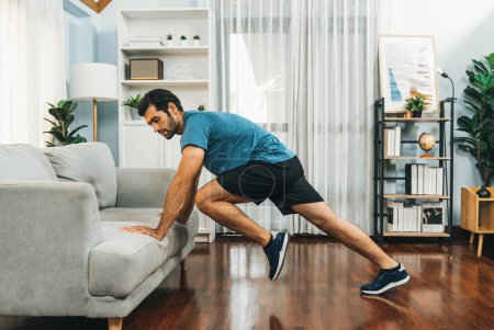 Photo for Athletic body and active sporty man using furniture for effective targeting muscle gain exercise at gaiety home exercise as concept of healthy fit body home workout lifestyle. - Royalty Free Image