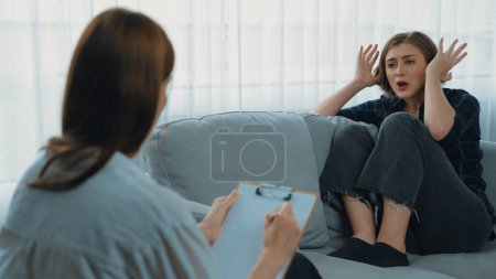 Photo for Sad PTSD woman patient in therapy for mental health with psychologist, depression or grief after life failure. Frustrated trauma young woman talking to prim psychologist about emotion in clinic - Royalty Free Image