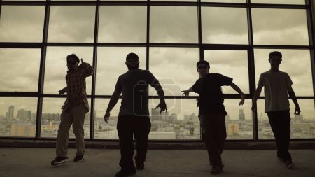 Photo for Silhouette shot of skilled choreographer group dancing together with sky scrapper, cityscape background. Young hipster team dancing performance. Sepia filter. Shadow. Outdoor sport 2024. Endeavor. - Royalty Free Image
