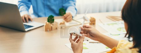 Photo for Businesswoman interested in investing in renewable energy at meeting table with environmental document scatter around. Business team discussion about green business project. Closeup. Delineation. - Royalty Free Image