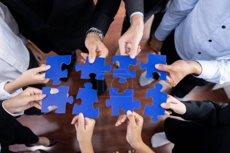 Téléchargez les photos : Les gens d'affaires multiethniques de vue supérieure tenant des pièces de puzzle et les fusionnent comme solution efficace résolvant le travail d'équipe, la vision partagée et l'objectif commun combinant divers talents. Méticuleux - en image libre de droit