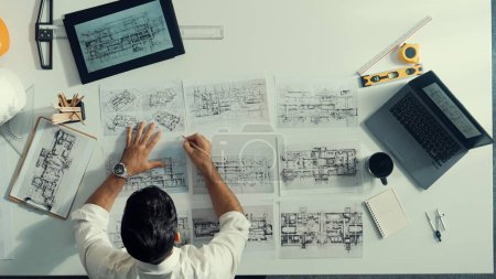 Photo for Top view of skilled civil engineer sitting and writing idea while looking at house model. Aerial view of architect or designer planning and thinking about creative building construction. Alimentation. - Royalty Free Image