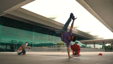 Photo for Group of diverse hipster or street dancer doing head spin in front of mall. Happy energetic break dancer practice b-boy step dancing with friends. Outdoor sport 2024. Street dancer concept. Sprightly. - Royalty Free Image