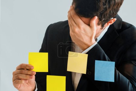 Photo for Serious businessman feels disappointed while looking at sticky note on the windows in the office. Bankruptcy and failure concept. uds - Royalty Free Image