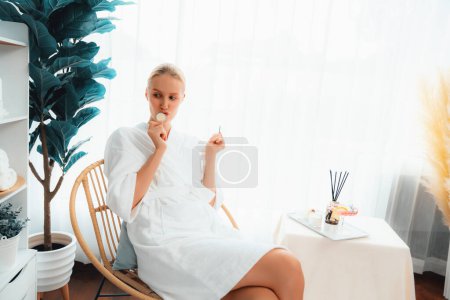 Photo for Woman holding slices of fresh cucumber and wearing bathrobe enjoying luxurious facial skincare spa in resort or hotel. Skin treatment for face and beauty care. Quiescent - Royalty Free Image