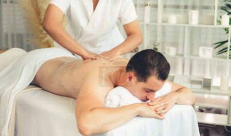 Photo for Caucasian man customer enjoying relaxing anti-stress spa massage and pampering with beauty skin recreation leisure in day light ambient salon spa at luxury resort or hotel. Quiescent - Royalty Free Image