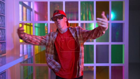 Photo for Funny break dancer moving freestyle step to hiphop while looking at camera. Crazy happy hipster dancing and performing street dancing while wear casual outfit and sunglasses in Led light. Regalement. - Royalty Free Image