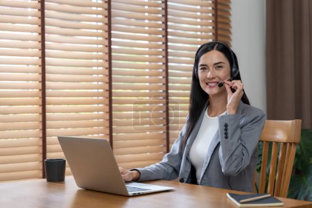 Photo for Female call center operator or customer service helpdesk staff working on workspace while talking on the headset to provide assistance for customer. Professional modern business service. Blithe - Royalty Free Image