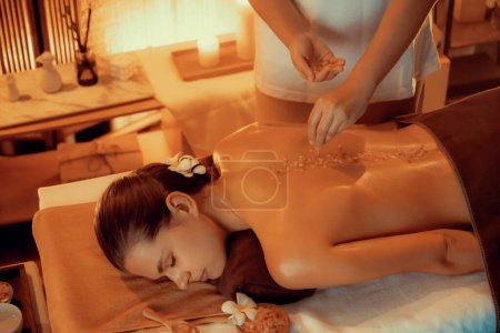 Photo for Woman customer having exfoliation treatment in luxury spa salon with warmth candle light ambient. Salt scrub beauty treatment in Health spa body scrub. Quiescent - Royalty Free Image