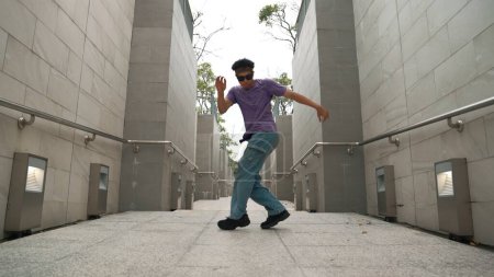 Téléchargez les photos : Un danseur professionnel danse de rue dans un couloir étroit. habile heureux asiatique hipster passer à la musique tandis que montrer b-boy étape à étroit mur. Style de vie moderne. Sport de plein air 2024. Brillamment. - en image libre de droit