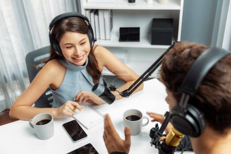 Host channel broadcaster with special guest making advice for problem in live streaming with listeners surrounded sets of live streaming on radio talking show at comfy modern workplace. Postulate.