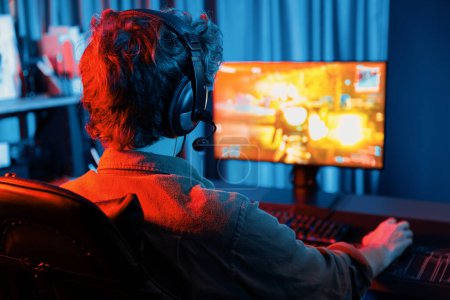 Host-Kanal von jungen Gaming-Streamer, Team-Gamer, die Battle Game Shooting mit Multiplayer auf Kriegsschiff auf dem PC-Bildschirm mit Rückseite Bild, trägt Headset mit Mikrofon im digitalen Neon-Raum. Gusher.