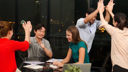 Téléchargez les photos : Groupe de gens d'affaires applaudissent les mains et donne cinq ensemble pour célébrer le projet de succès, de bonnes nouvelles. Équipe d'affaires applaudissements pour célébrer la promotion à la table de réunion au bureau de nuit. Traçabilité - en image libre de droit