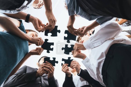 Photo for Below view of diverse corporate officer workers collaborate in office connecting puzzle pieces as partnership and teamwork concept. Unity and synergy in business idea by merging jigsaw puzzle. Concord - Royalty Free Image