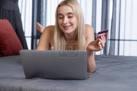 Junge Frau nutzt Laptop mit Kreditkarte für Internet-Banking, Online-Shopping E-Commerce durch Online-Zahlungsportal im Home Office. Moderner und bequemer Online-Einkauf mit EC-Karte. Glückseligkeit