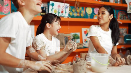 Photo for Caucasian highschool girl modeling cup of clay while looking smart boy in art class at workshop. Multicultural student playing or making cup of clay art in creative activity. Education. Edification. - Royalty Free Image