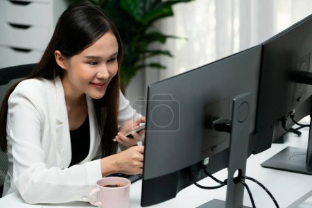 Téléchargez les photos : Sourire jeune femme d'affaires asiatique à la recherche marketing stratégie en ligne à l'aide d'un smartphone pour analyser le rapport de chiffre comparer avec pc dans l'analyse des affaires pour faire cible de ventes dans les entreprises commerçantes. Stratagème. - en image libre de droit