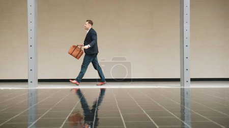 Photo for Side view of business people holding suitcase and walking to workplace along the street in urban city. Professional project manager going to meeting while wearing formal suit walk at outdoor. Urbane. - Royalty Free Image