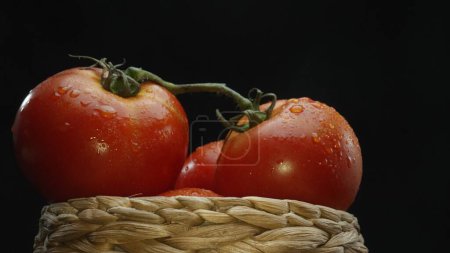 Téléchargez les photos : Macrographie, tomates nichées dans un panier en bois rustique sont exposées sur un fond noir dramatique. Chaque gros plan capture les riches couleurs et textures des tomates. Comestible. - en image libre de droit