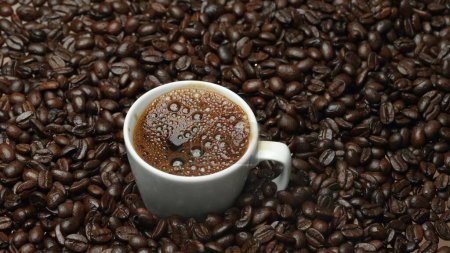 Primer plano de la burbuja aromática de café caliente en la taza con fondo negro. Café caliente o espresso se vierte en taza de café blanco cayendo en agua hervida con fondo negro separado. Comestible.