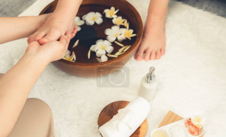 La mujer se complace en el masaje de pies dichosos en el lujoso salón de spa, mientras que el masajista da terapia de reflexología en un suave resort de ambiente de luz diurna o un spa de pies de hotel. Silencioso.