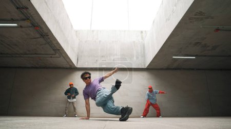 Photo for Group of stylish hipster perform dancing together in building. Happy break dancer enjoy moving to hip hop music with freestyle dance surrounded by street dancer team. Outdoor sport 2024. Sprightly. - Royalty Free Image