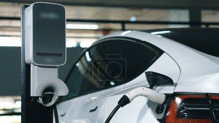 Photo for EV electric car recharge at shopping center multistorey indoor parking lot charging in downtown city showing urban sustainability green clean rechargeable energy lifestyle of electric vehicle innards - Royalty Free Image