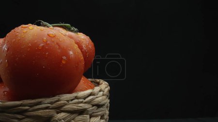Photo for Macrography, tomatoes nestled within a rustic wooden basket are showcased against a dramatic black background. Each close-up shot captures the rich colors and textures of the tomatoes. Comestible. - Royalty Free Image