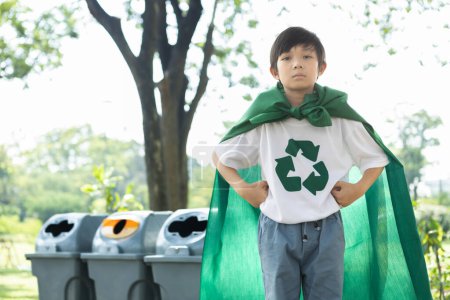 Foto de Muchacho alegre y joven superhéroe con capa y símbolo de reciclaje que promueve el reciclaje de residuos, reducir y reutilizar el estímulo como faro de conciencia ecológica sostenible para la generación futura. Gyre. - Imagen libre de derechos