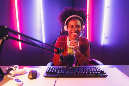 Photo for Host channel of gaming streamer, African girl taking, typing with Esport skilled team player and viewers online game in neon color lighting room. Concept of cybersport indoor activities. Tastemaker. - Royalty Free Image