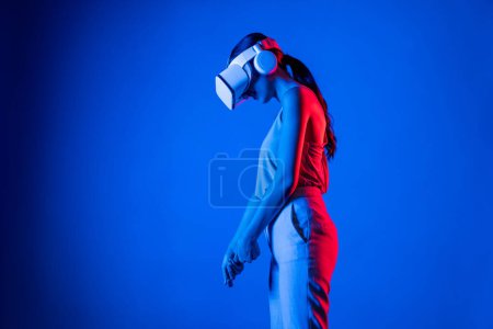 Téléchargez les photos : Femme intelligente portant un casque VR connectant la métaverse, future technologie de la communauté cyberspatiale. Femme élégante calcul et contrôle putter virtuel sérieusement jouer à des jeux de golf. Hallucination. - en image libre de droit