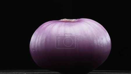 Macrography of peeled red onion against a sleek black background takes center stage. Each close-up shot meticulously captures the intricate details and textures of the onion. Close up. Comestible.