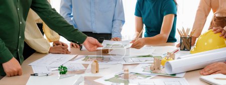Photo for Professional architect engineer team discussion about architectural project on meeting table with wooden block and blueprint scatter around. Design and cooperate concept. Closeup. Delineation. - Royalty Free Image