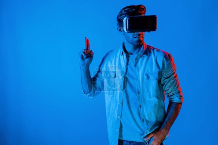 Foto de Hombre elegante caucásico con gafas VR y gesto en movimiento sosteniendo la pistola. Gamer utilizando futuros auriculares de realidad virtual digital o innovación futurista para entrar en el mundo meta o jugar juego de acción. Desviación. - Imagen libre de derechos