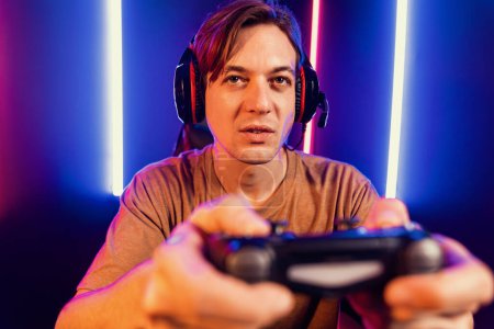 Photo for Enjoy smart gaming streamer with control joystick, playing game online of live streaming social media group with team skilled players on computer at modern technology cyber neon light room. Pecuniary. - Royalty Free Image