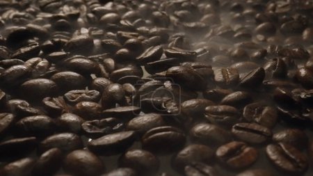 Photo for Close up of fresh brown coffee bean with roasted smoke from pile of coffee beans. Macrography of hot coffee seed with fragrant and scented hot smoke come from pile of bean. Top down view. Comestible. - Royalty Free Image