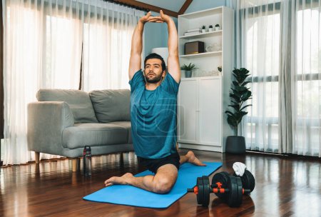 Photo for Athletic and sporty man doing warmup and stretching before home body workout exercise session for fit physique and healthy sport lifestyle at home. Gaiety home exercise workout training concept. - Royalty Free Image