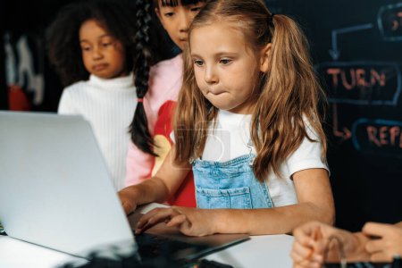 Photo for Smart girl in white bib learning about coding robotics technology using laptop in the STEM class. Schoolboy in blue shirt try to educate motherboard while smart schoolgirls reading code. Erudition. - Royalty Free Image
