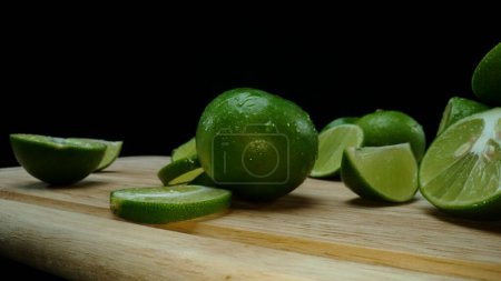 Photo for Close-up, a vibrant slice of fresh lime rests upon a rustic wooden cutting board, exuding freshness and vitality. The translucent membranes of the green lime slice placed on cutting board. Comestible. - Royalty Free Image