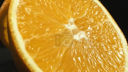 Foto de Una captura macrográfica de una rebanada de naranja, colocada sobre un fondo negro elegante y aislado, se despliega como una obra maestra visual de encanto cítrico. Una rebanada de naranja con fondo negro. Comestible. - Imagen libre de derechos