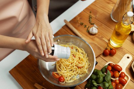 Primer plano de la mano chef influencer cocinar espaguetis mezcla ingrediente tomando a sartén, poniendo condimento y salsa sabrosa para hacer buen sabor, Concepto de presentar comida casera en el estudio. Postulado.
