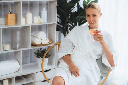 Photo for Beauty or body treatment spa salon vacation lifestyle concept with woman wearing bathrobe relaxing with drinks in luxurious hotel spa or resort room. Vacation and leisure relaxation. Quiescent - Royalty Free Image