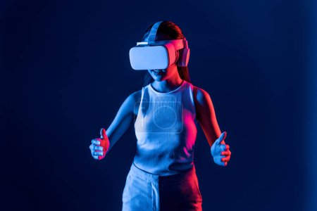 Photo for Smart Female standing surrounded by neon light wear VR headset connecting metaverse, futuristic cyberspace community technology, using both hands interact with generated virtual object. Hallucination. - Royalty Free Image