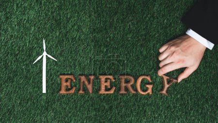 Hand arrange wooden alphabet in ECO awareness campaign on biophilia green grass background o promote eco-friendly energy and limited power consumption to reduce CO2 emission for sustainable Earth.Gyre