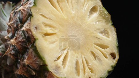 Photo for Close up video of fresh pineapple with slice of peel pineapple insert with separated black background. The rough and waxy rind, boasting a crown of spiky green leaves, Food photography. Comestible. - Royalty Free Image