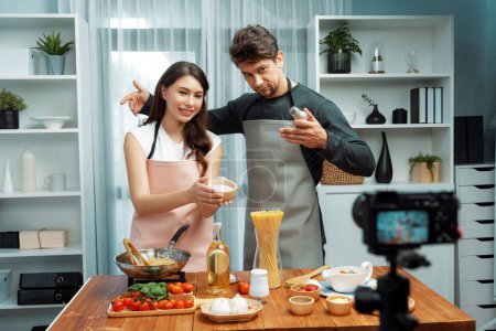 Photo for Couple chef influencers on cooking show presenting ingredient of spaghetti, meat, chilli, tomato, garlic and seasoning sauces homemade special recipe recording on camera on live channel. Postulate. - Royalty Free Image